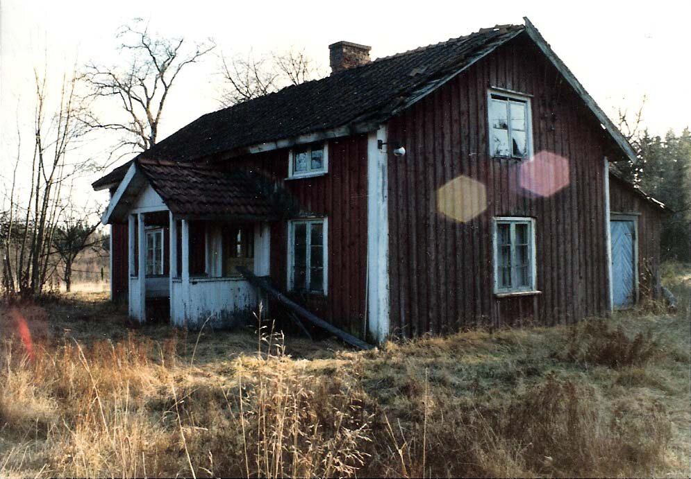 Äldre rödmålat bostadshus med veranda och vita snickerier