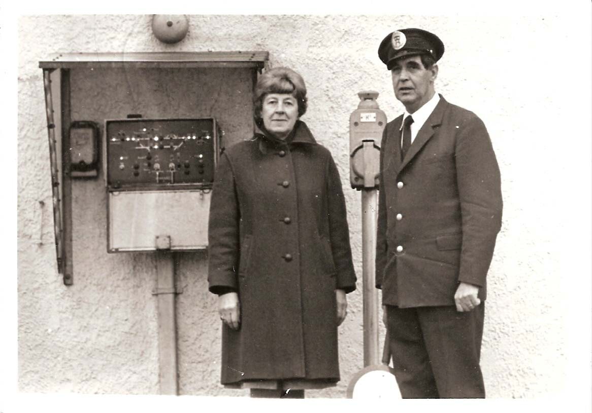 En kvinna och en uniformerad man intill äldre järnvägsutrustning