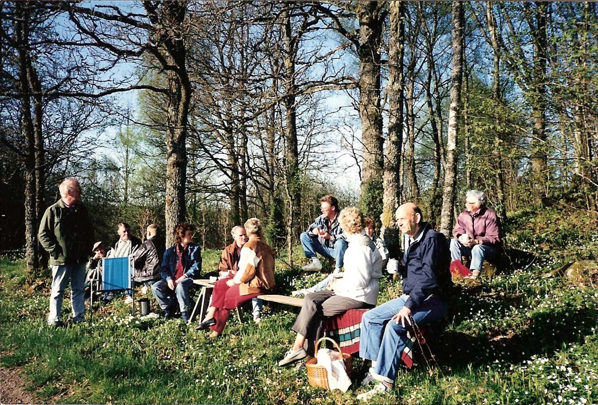 En grupp människor samlade i en skogsglänta på våren